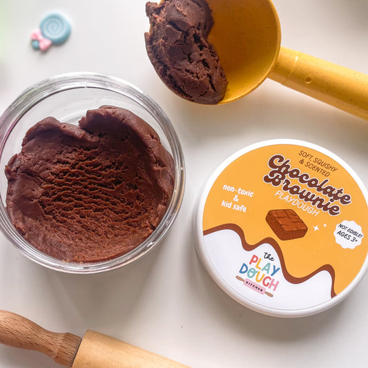 Chocolate play dough in a container with tools on a white background