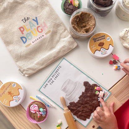 Children's play dough kit with play dough, tools, and a play dough activity mat on a table.