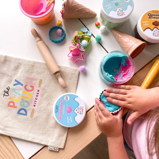 Children's play dough kit with tools and containers on a table.