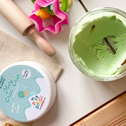 Mint choc chip play dough in a tub with a lid on a kitchen counter.