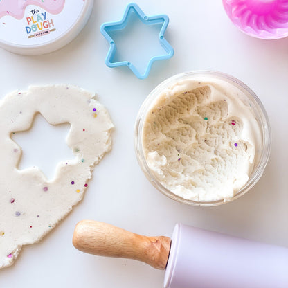 A jar of creamy white playdough with colourful glitter on a white background