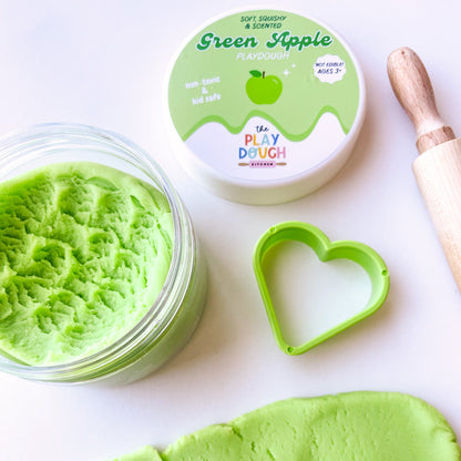 Green apple playdough in a jar with a rolling pin and cookie cutter