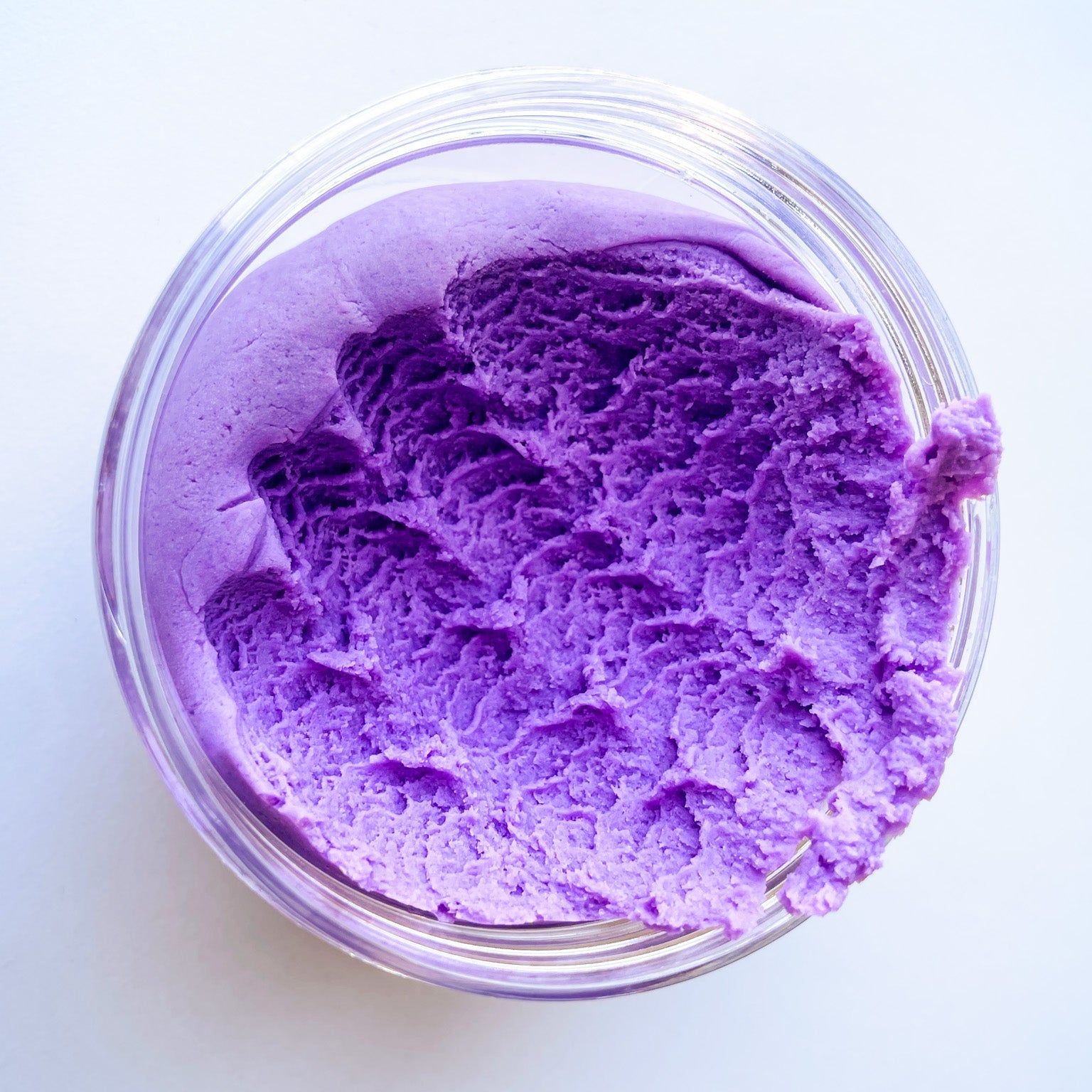Purple granadilla play dough in a clear jar on a white surface