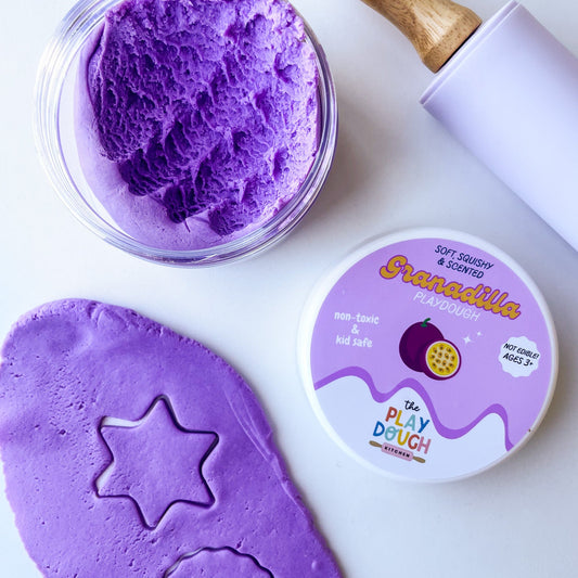 Purple granadilla playdough in a tub on a white surface
