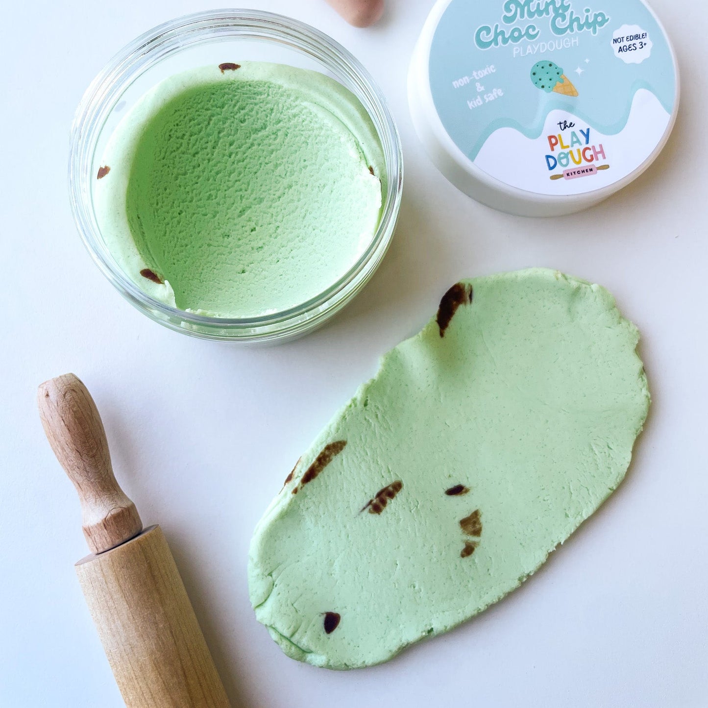 Green play dough with a wooden rolling pin, container labeled 'Mint Choc Chip', and ice cream cone on a white background.